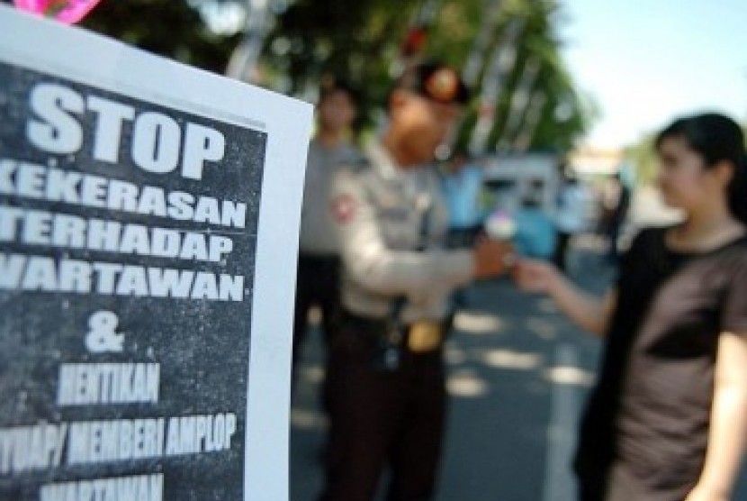 Seorang wartawan membagi-bagikan bunga kepada aparat kepolisian saat melakukan aksi bersama puluhan wartawan lainnya dalam rangka memperingati Hari Pers se-Dunia di Monumen Mandala Makassar, Sabtu (3/5). Dalam aksinya, mereka menuntut dihentikan segala ben