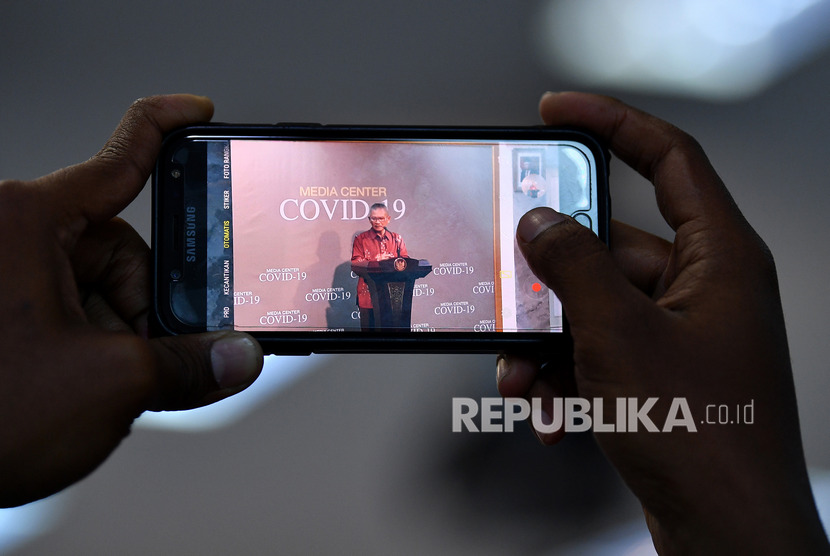 Seorang wartawan merekam juru bicara pemerintah untuk penanganan COVID-19 Achmad Yurianto saat memberikan keterangan pers di Kantor Presiden, Jakarta, Rabu (11/3/2020).(Antara/Sigid Kurniawan)