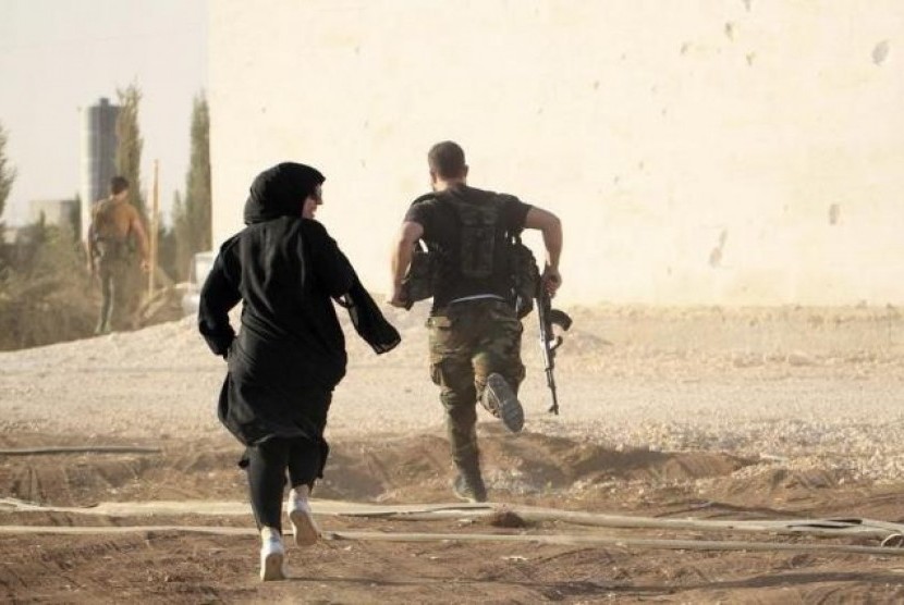 Seorang wartawan perempuan berlari bersama pemberontak menghindari penembak jitu di Aleppo, Suriah.