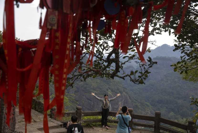 Seorang wisatawan mengambil foto di Puncak Tianoyou di Wuyishan, Provinsi Fujian, Cina, Rabu (14/8). Aktivitas sektor jasa di Cina meningkat ke level tertinggi sejak tujuh bulan terakhir pada November.