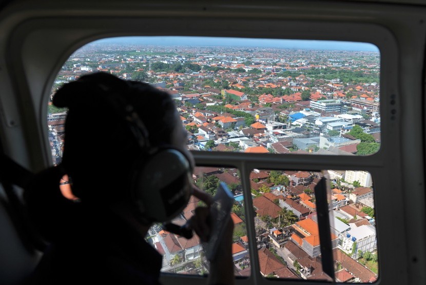 Seorang wisatawan menikmati pemandangan Bali dari udara. Ilustrasi