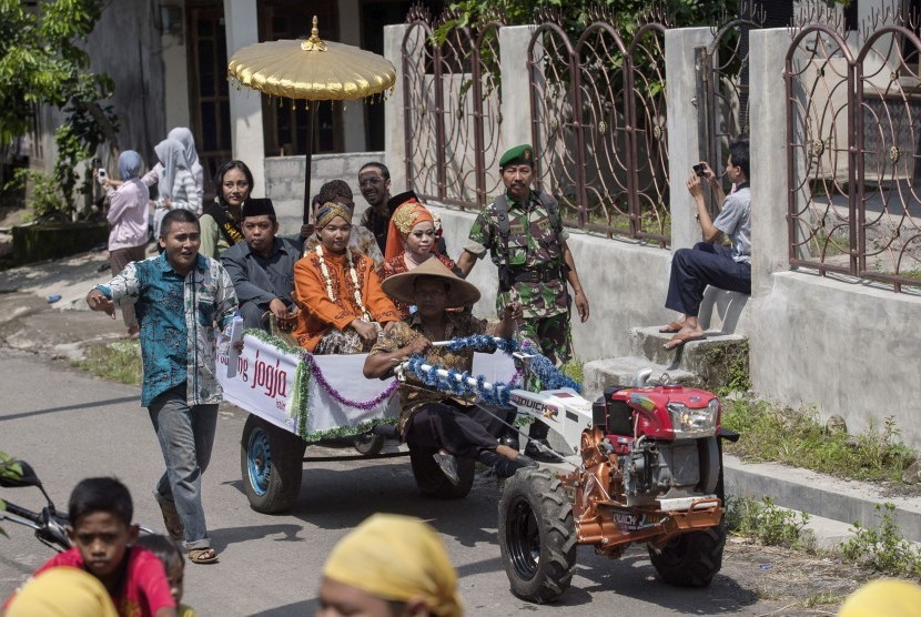 Sepasang pengantin diarak dengan traktor dalam acara Nikah Bareng Jogja Istimewa di Alas Kradenan, Piyungan, Bantul, Yogyakarta, Sabtu (28/3).