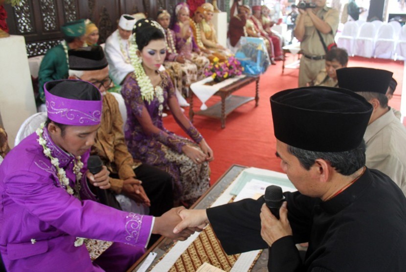 Sepasang pengantin melakukan ijab kabul pada pernikahan massal di rumah dinas Bupati Sleman, Senin (13/5). Pemkab Sleman mengakomodir pasangan - pasangan yang ingin menikah namun terkendala biaya