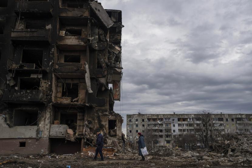 Sepasang suami istri berjalan di depan bangunan apartemen yang hancur di kota Borodyanka, Ukraina, pada Sabtu, 9 April 2022. Amerika Serikat (AS) dan Inggris menuduh Rusia menyebarkan informasi palsu dan memanipulasi opini publik tentang perang di Ukraina. 