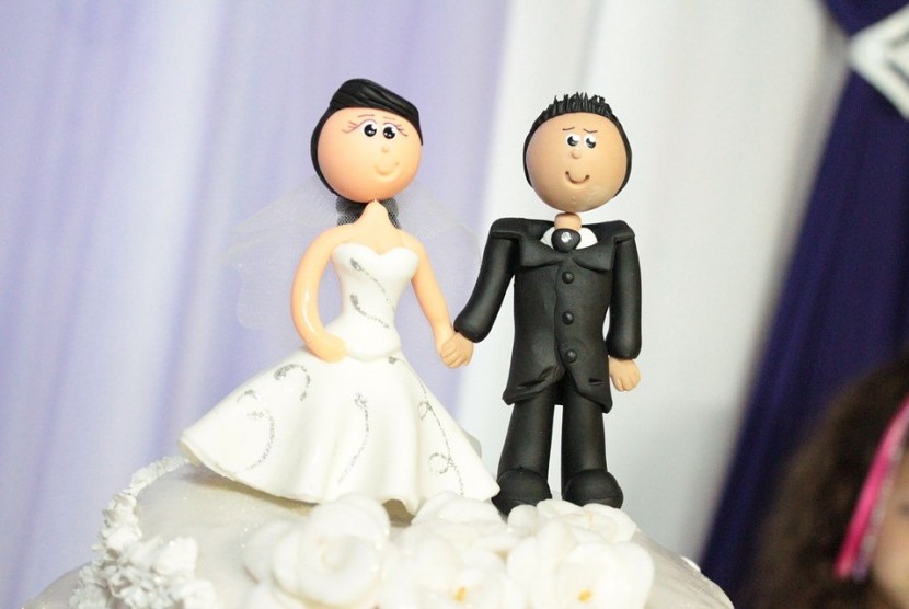 Sepasangan suami istri tergambar di atas kue perkawinan.