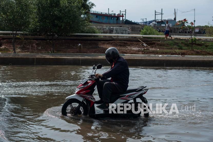 Pengendara motor melintasi banjir rob di kawasan Pelabuhan Perikanan Samudera Nizam Zachman, Muara Baru, Penjaringan, Jakarta Utara, Sabtu (6/11/2021).