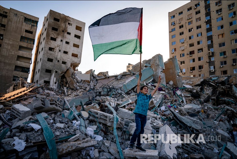  Serang anak mengibarkan Palestina berdiri di atas reruntuhan gedung Al Jalaa yang hancur oleh serangan udara Israel, Gaza, Jumat (21/5) waktu setempat.  Sejumlah media internasional menempati gedung Al-Jalaa termasuk kantor berita Associated Press yang telah berkantor disana selama 15 tahun.  Ratusan warga Gaza berjalan melewati reruntuhan sebuah gedung yang hancur oleh serangan udara Israel, Gaza, Jumat (21/5) waktu setempat.