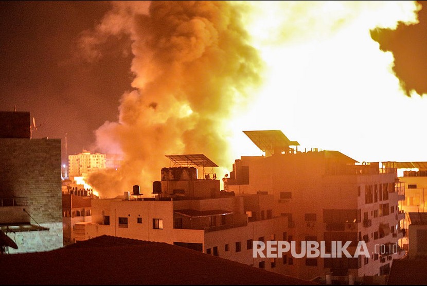 Asap dan api membubung dari gedung yang menjadi target pengeboman saat serangan udara militer Israel ke Kota Gaza, Palestina, Selasa (18/5). 