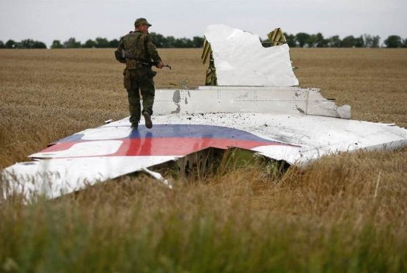Serdadu Ukraina pro-Rusia berjalan di atas puing pesawat MH-17 milik maskapai Malaysia Airlines yang jatuh di dekat Desa Grabovo, Donetsk, Ukraina, Kamis (17/7).
