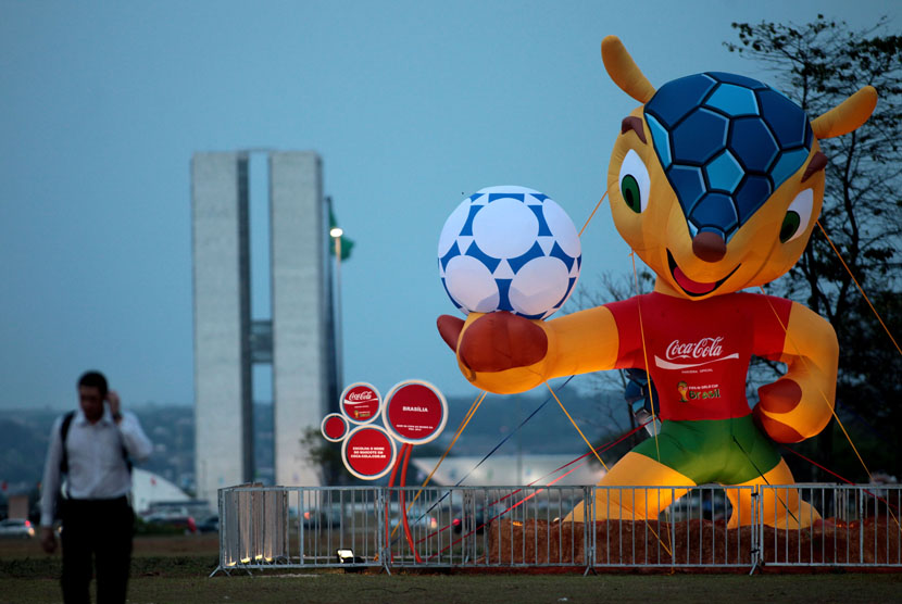 Seseorang berjalan melewati maskot Piala Dunia 2014, Fuleco, di kota Brasilia. 