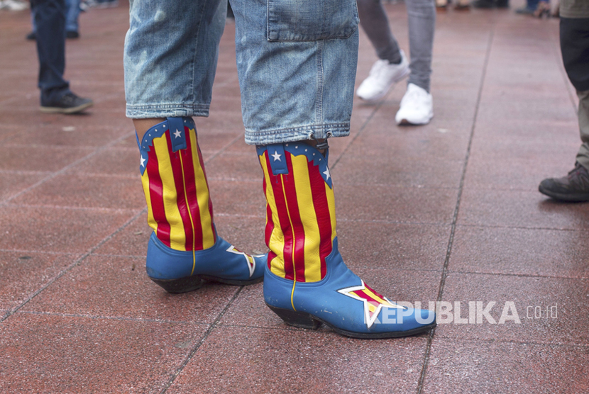 Seseorang memakai sepatu bot dengan warna bendera Catalonia di Barcelona,  Spanyol, (1/10).   