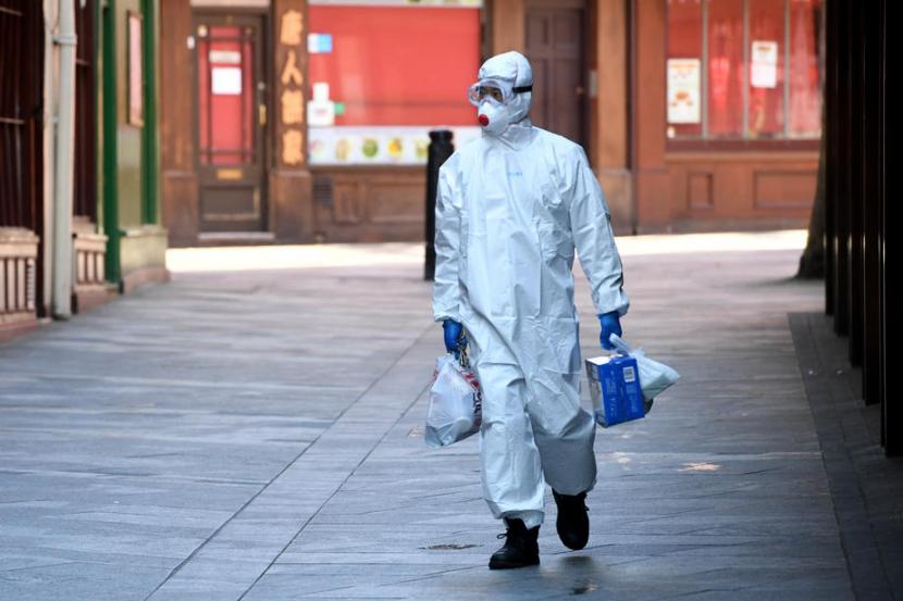 Seseorang mengenakan APD berjalan di London, Inggris (2/5). Inggris memasuki pekan keenam lockdown untuk mengontrol penyebaran virus corona.