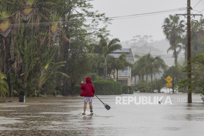 Seseorang menggunakan papan dayung di jalan yang banjir di Port Macquarie, utara Sydney, Australia, Jumat, 23 Mei 2025.