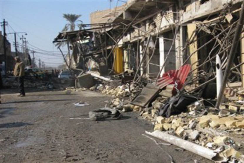 Seseorang pria tengah berdiri di sekitar lokasi ledakan bom di Kazimiyah, utara Baghdad, Kamis (5/1).