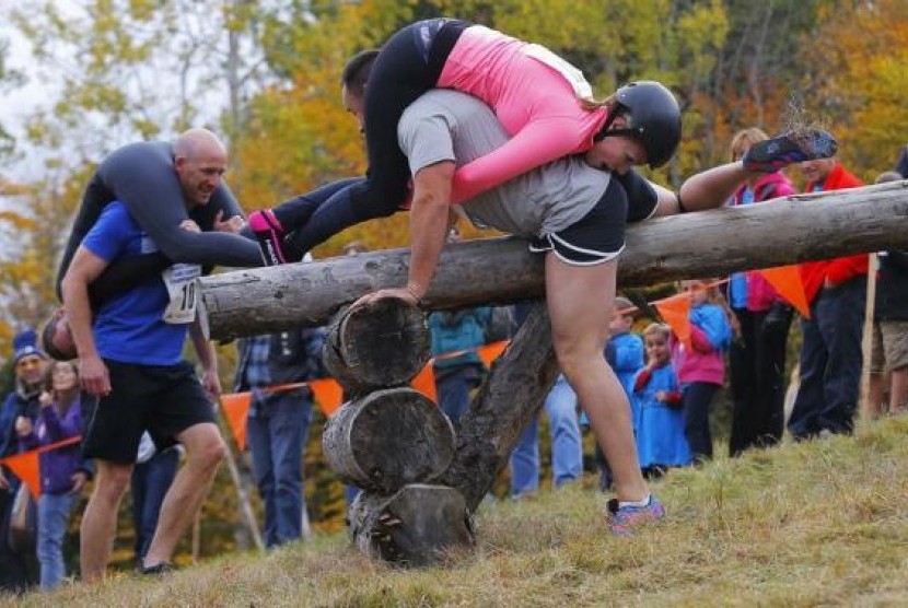 Shane Arnold and Brandy Bates clear the second obstacle ahead of Ian and Susan Bell (left) while competing in the North American Wife Carrying Championship at Sunday River ski resort in Newry, Maine October 11, 2014.  