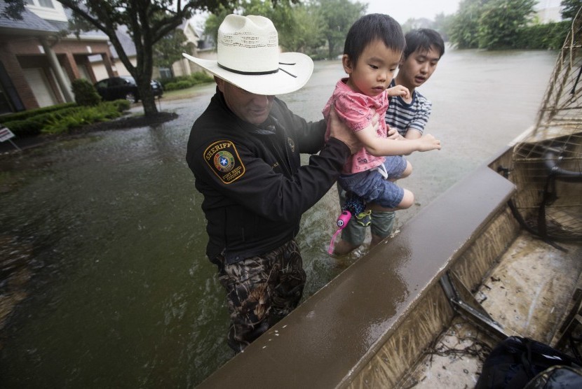 Sherrif dari Fort Bend County membantu korban banjir akibat Badai Harvey di kawasan Orchard Lakes Subdivision, Texas, (28/8).