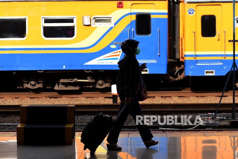   Shiluet penumpang melintas membawa koper ketika menunggu kedatangan kereta api.