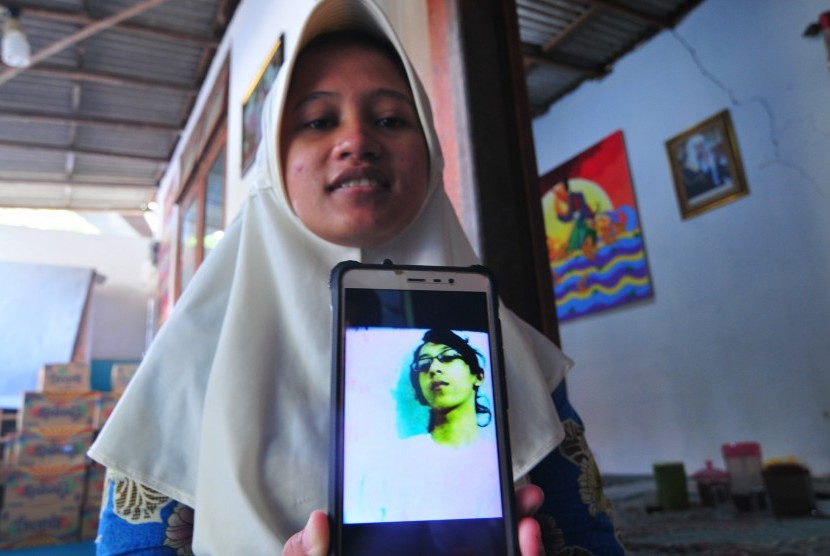Sianit Sinta menujukkan foto alhamrhum suaminya Ahmad Budi Cahyanto, guru SMAN 1 Torjun yang tewas dipukul siswanya sendiri, di Desa Tanggumung, Sampang, Jawa Timur, Sabtu (3/2).   