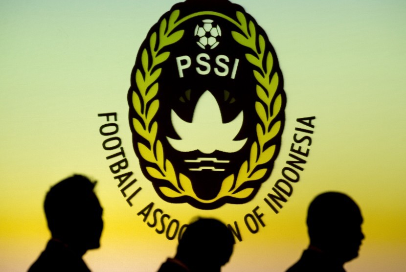 Siluet sejumlah orang di depan logo PSSI.