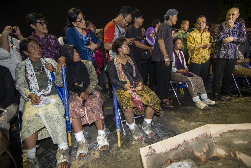 Simpatisan melepas semen yang memasung kaki petani Kartini Pegunungan Kendeng yang menggelar aksi di depan Istana Merdeka, Jakarta, Rabu (13/4).