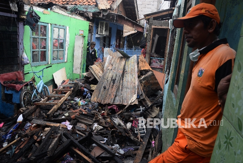 Petugas membersihkan puing sisa kebakaran yang melanda permukiman padat penduduk di kawasan Petamburan, Tanah Abang, Jakarta.