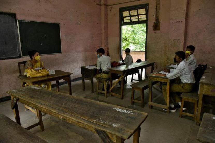 Siswa dan guru mereka mengenakan masker pelindung wajah di dalam ruang kelas di tengah wabah Covid-19 di Guwahati pada 21 September 2020.