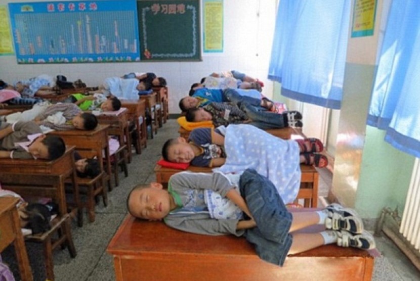 Siswa di Cina sedang tidur siang di atas meja belajar.