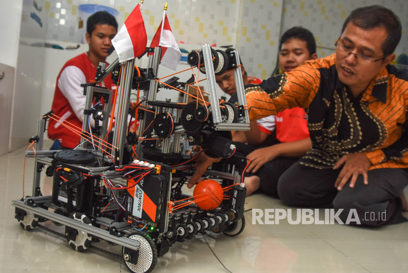 Siswa Madrasah Aliyah TechnoNatura yang tergabung dalam tim Never Before bersama Kepala Sekolah Tras Rustamaji (kanan) mempraktikkan kinerja robot WowWi karya mereka di Kelapa Dua, Depok, Jawa Barat, Kamis (3/8). 