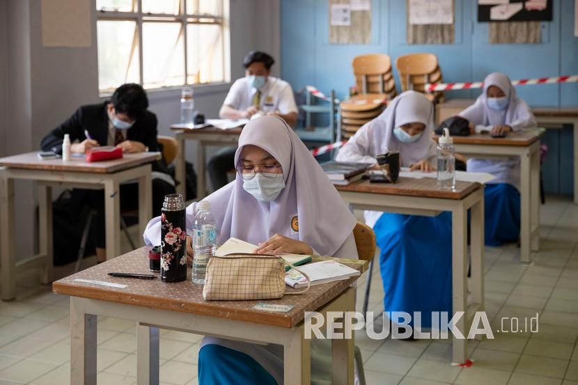Guru Tolak Tuduhan Sekolah Negeri Malaysia Terlalu Islami. Siswa mengenakan masker dan menjaga jarak sosial di ruang kelas selama hari pertama sekolah dibuka kembali di sebuah sekolah menengah di Putrajaya, Malaysia.