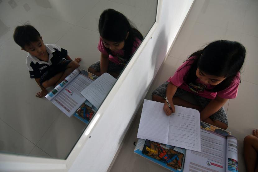 Palu Gencarkan Vaksinasi Siswa untuk Keamanan PTM. Siswa mengerjakan tugas sekolah di rumahnya di Kota Palu, Sulawesi Tengah.