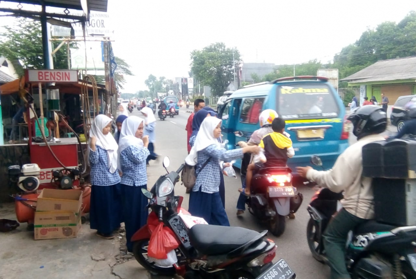 Siswa MTsN 1 Bogor merayakan kelulusan sekolah dengan cara yang unik, yakni dengan membagi-bagikan takjil kepada pengguna jalan di sekitar sekolah mereka di Lebak Wangi, Bogor.