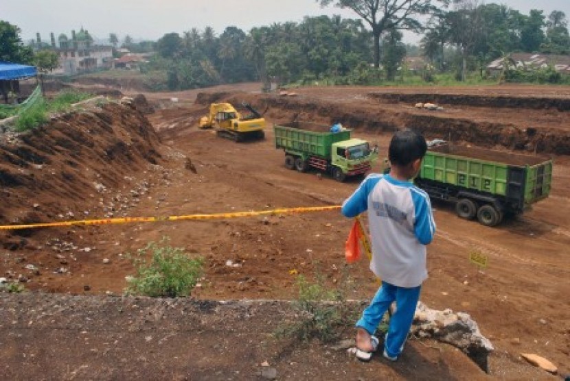 Siswa SD menyaksikan sejumlah truk dan alat berat mengangkut pasir dalam proyek pembangunan Jalan Tol Bogor-Ciawi-Sukabumi (Bocimi) di Kampung Harjasari, RT 01 RW 06, Kota Bogor, Jawa Barat, Selasa (3/11).