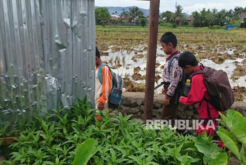 Siswa SDN 43 Sungai Sapih Kota Padang harus lewat tepi sawah untuk menuju sekolah karena jalan utama yang biasa ditempuh ditutup dengan pelat seng oleh pemilik tanah. 