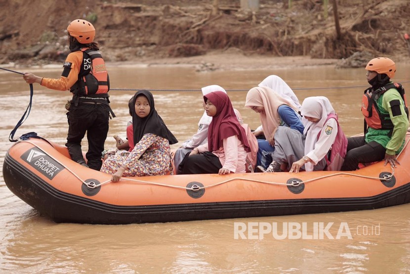 Tim Water Rescue DMC (Disaster Management Centre) Dompet Dhuafa membantu siswa SDN 1 Sajira, Kabupaten Lebak, menyeberangi Sungai Ciberang untuk menuju sekolahnya. 