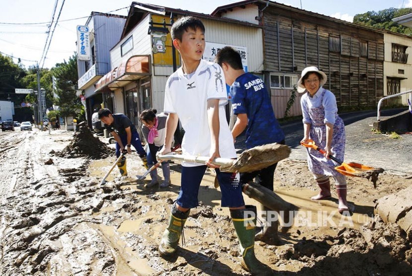 Siswa sekolah dan warga setempat membersihkan jalanan dari lumpur yang terbawa banjir di Marumori, Miyagi prefecture Jepang utara setelah  Hagibis menghantam kota tersebut , Ahad (13/10).. 