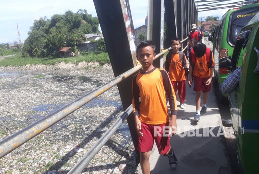 Siswa Sekolah Dasar tengah berjalan kaki di jembatan Citarum lama. Kondisi sungai Citarum lama yang tidak aktif dipenuhi dengan sampah dan air limbah pabrik.