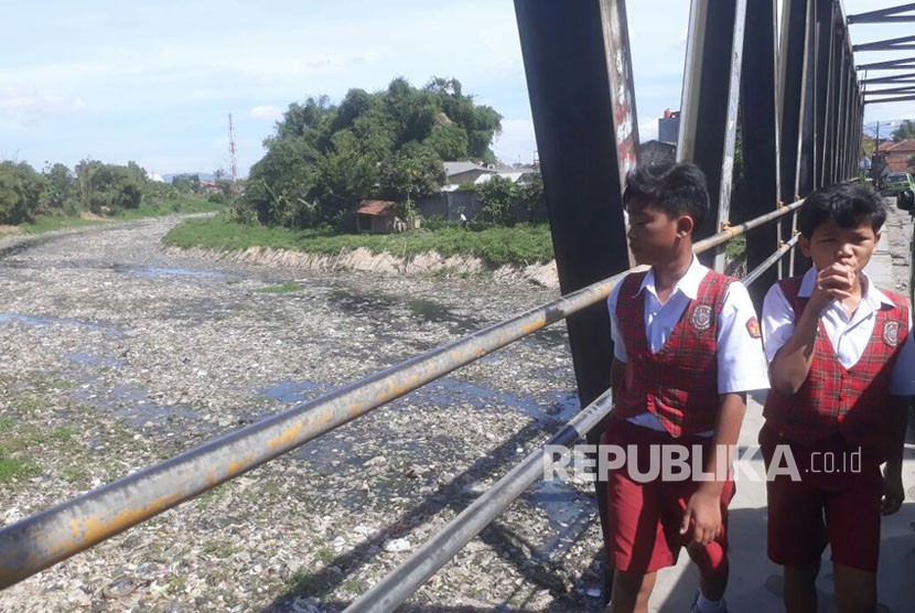 Siswa Sekolah Dasar tengah berjalan kaki di jembatan Citarum lama, Senin (19/2). Kondisi sungai Citarum lama yang tidak aktif dipenuhi dengan sampah dan air limbah pabrik.