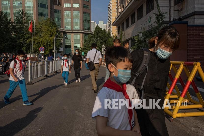  Siswa sekolah yang mengenakan masker pelindung berjalan dengan kerabat mereka untuk memasuki sekolah pada hari pertama semester baru, di Beijing, China, Rabu (1/9). Dua lembaga peradilan dan lembaga penuntutan tertinggi di China telah mengesahkan larangan mengajar seumur hidup bagi guru yang terlibat berbagai kasus.