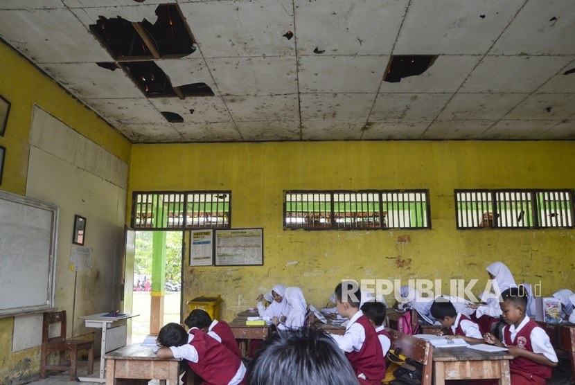 Siswa-siswi mengikuti kegiatan belajar mengajar di ruang kelas yang bagian atap rusak. Sekolah di Kudus yang mengalami kerusakan didata kembali. Ilustrasi.