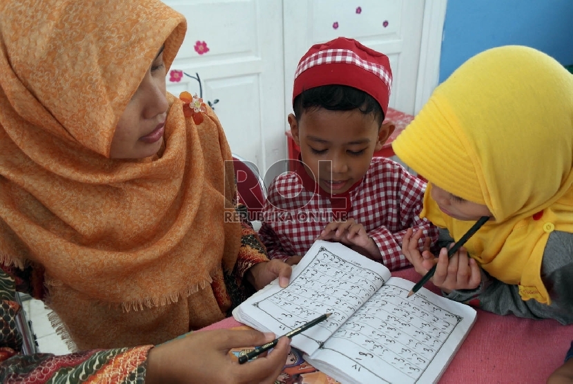 Seorang guru sedang mengajarkan membaca huruf arab