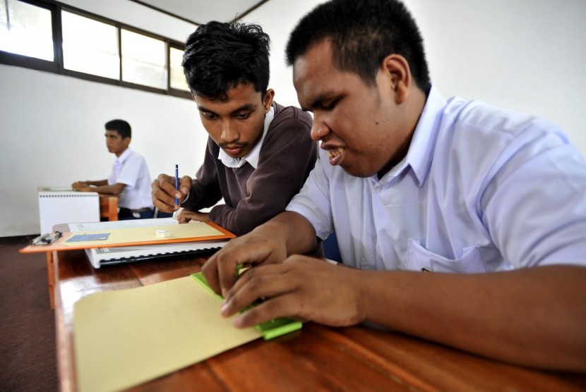 Siswa tuna netra didampingi pendampingnya menjawat pertanyaan saat mengikuti Ujian Nasional (UN) tingkat SMP di SLBA Yapti Makassar, Sulawesi Selatan, Senin (9/5).