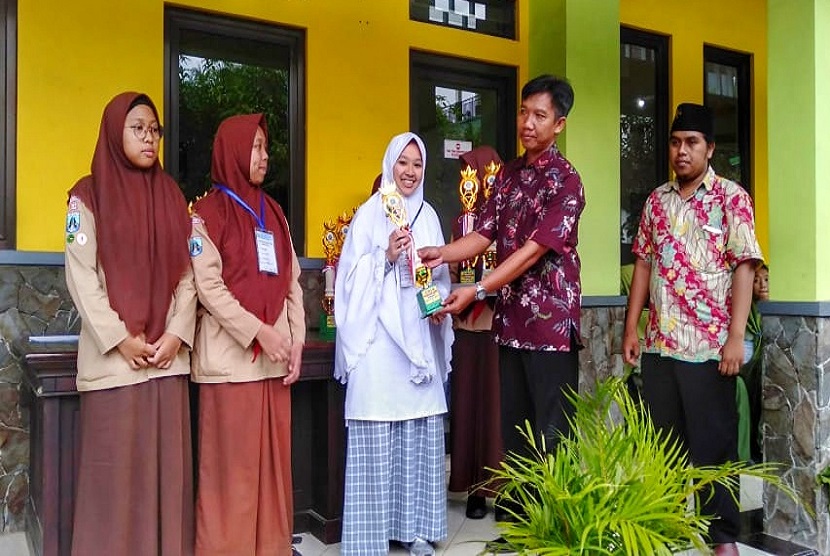 Siswi SMA Ar Rohmah Putri memegang piala Olimpiade Sains SMA Swasta Se-kabupaten Malang