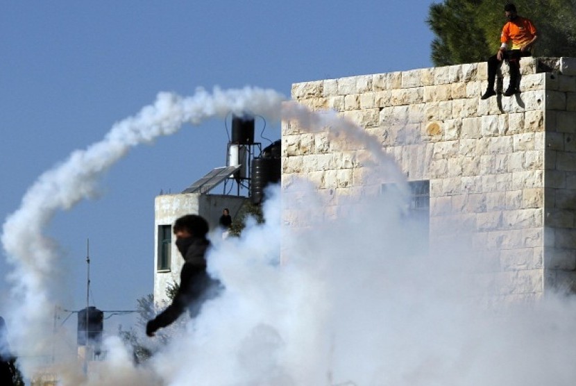 Smoke from a tear gas canister fired by Israeli security officers (unseen) rises in front of stone-throwing Palestinians. West Bank has seen mounting clashes between Israeli soldiers and Palestinian protestors, leaving two Palestinians dead since the launch on Nov. 14 of an eight-day Israeli offensive in the Gaza Strip.