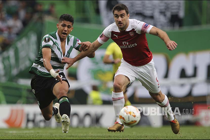 Sokratis Papastathopoulos (kanan) menarik jersey Fredy Montero (kiri) pada laga Grup E Liga  Europa antara Sporting CP melawan Arsenal di Alvalade stadium, Lisbon, Portugal, Jumat (26/10) dinihari.