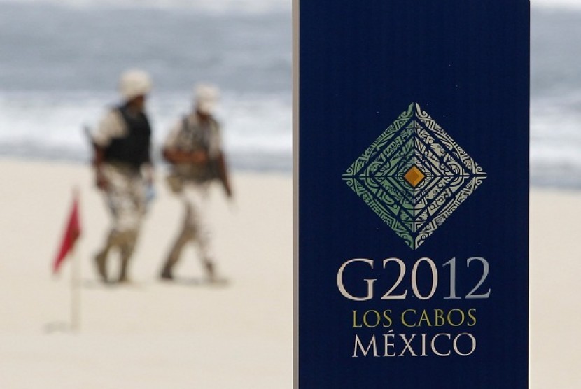 Soldiers walk near a sign of the G20 summit on a beach in Los Cabos June 17, 2012. G20 leaders will kick off two days of meetings in the Pacific resort of Los Cabos on Monday.   