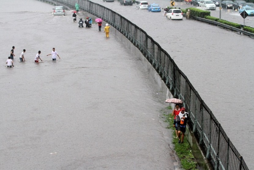 Some people trapped by flood try to cross the road near a toll road in Jakarta on Thursday. (illustration)