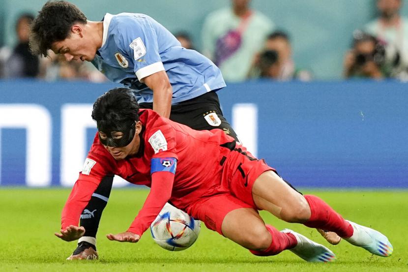  Son Heung-min dari Korea Selatan (di bawah) dan Facundo Pellistri dari Uruguay bertarung memperebutkan bola selama pertandingan sepak bola grup H Piala Dunia antara Uruguay dan Korea Selatan, di Stadion Education City di Al Rayyan, Qatar, Kamis, 24 November 2022. 