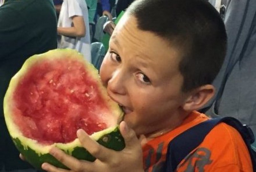Sosok anak laki-laki , yang diketahui bernama Mitch, tertangkap kamera sedang lahapnya menyantap semangka berukuran sebesar bola kaki ketika menonton pertandingan olahraga kriket.