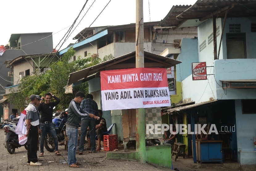 Warga memasang spanduk yang bertuliskan tuntutan ganti rugi atas penertiban permukiman di Kalijodo, Jakarta, Kamis (18/2).