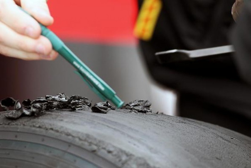 Staf Pirelli tengah memeriksa ban pecah dari salah satu kendaraan tim Formula 1.
